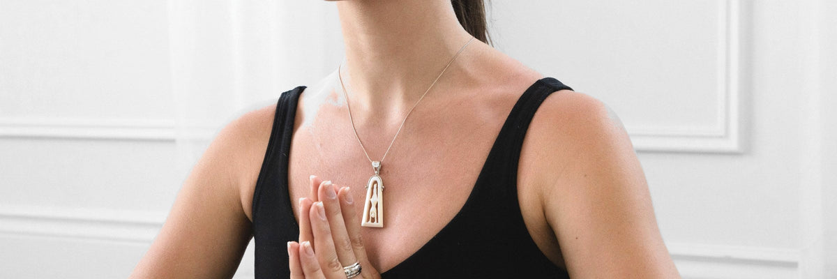 Woman in a meditation pose wearing an Energy Stone pendant and spinner ring